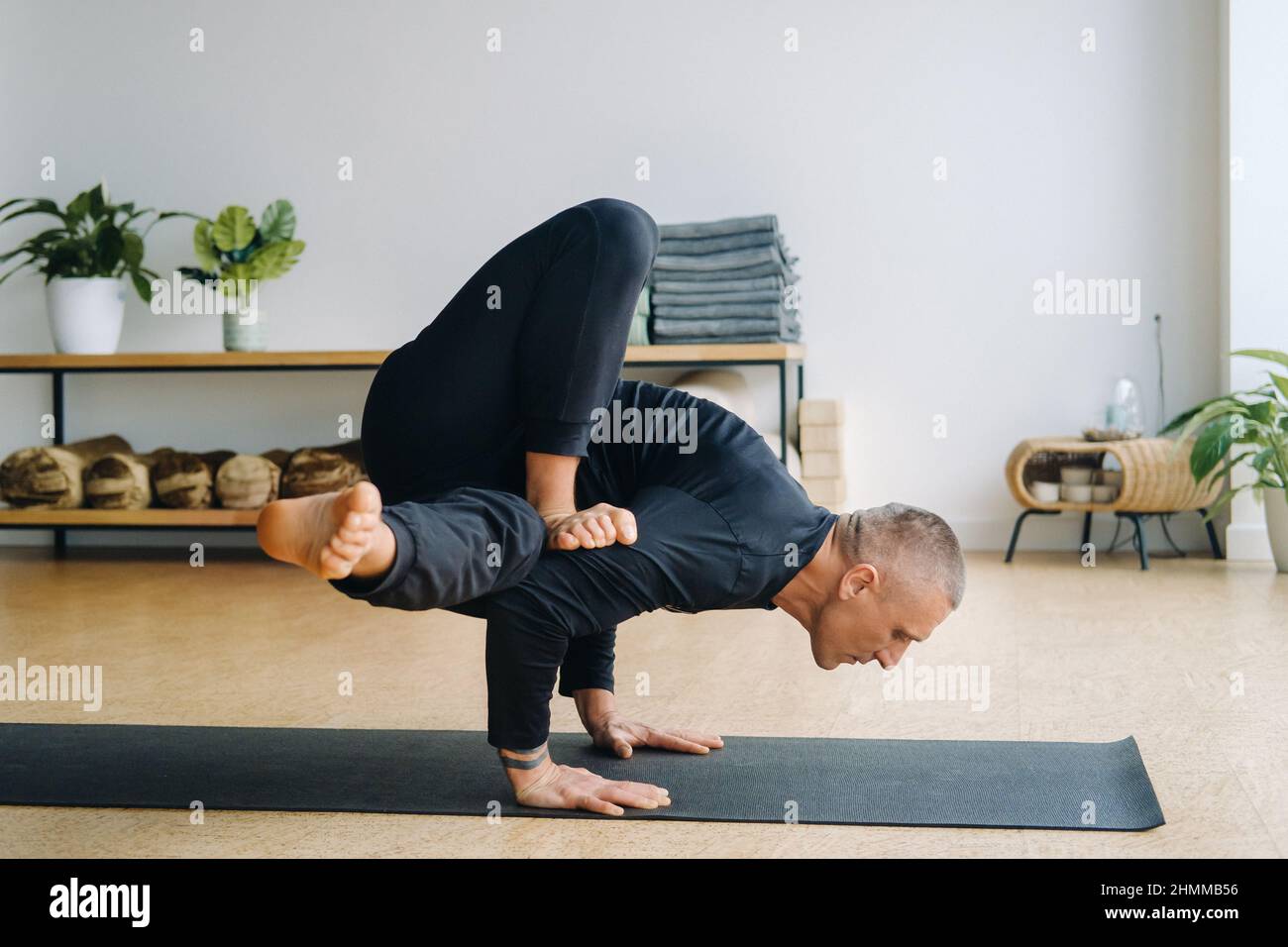 A man in black sportswear does yoga standing on his hands, stretching in  the gym Stock Photo - Alamy
