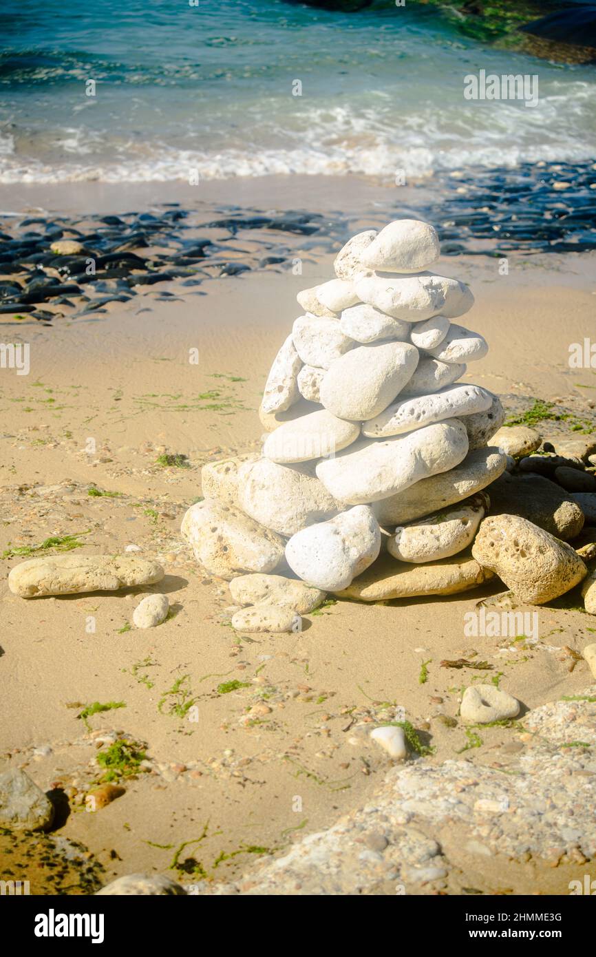 Pile of stone on the beach on the lighthouse Phare des Baleines on the isle of Ile de Ré in France on a sunny summerday Stock Photo