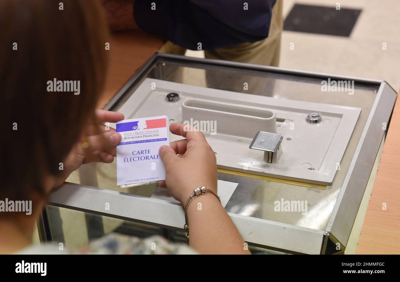 Polling station in Evreux (northern France) on 2017/06/11: someone holding a voter registration card in front of a ballot box on the occasion of the first round of the 2017 legislative election Stock Photo