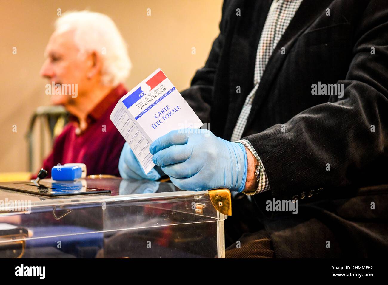 Local election: polling station in Rouen (northern France) on March 15, 2020. Assessor with disposable gloves holding a voter registration card Stock Photo