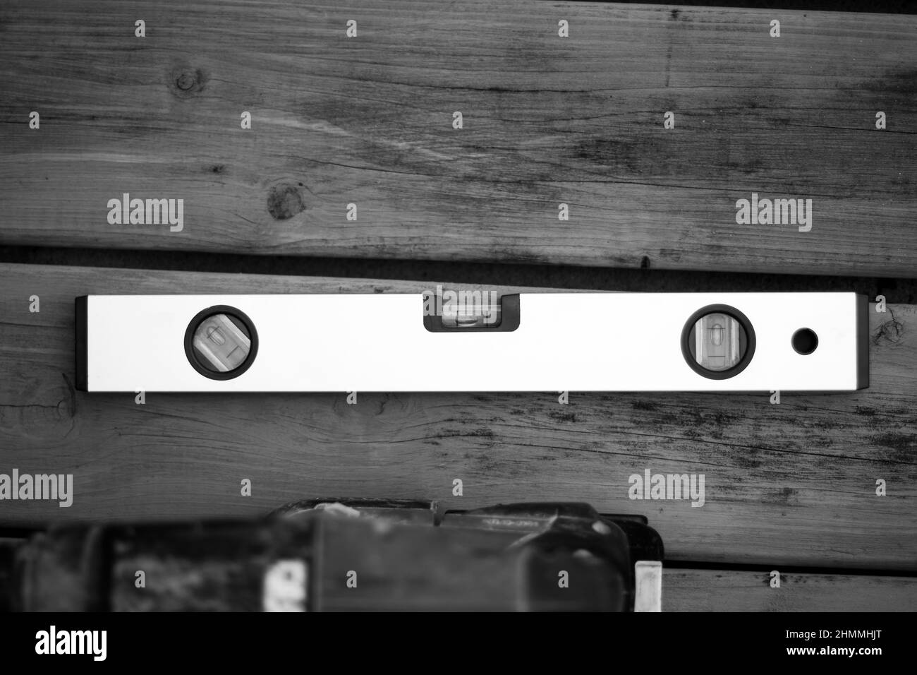 Black and white picture of a spirit level ruler on a wooden background. Stock Photo