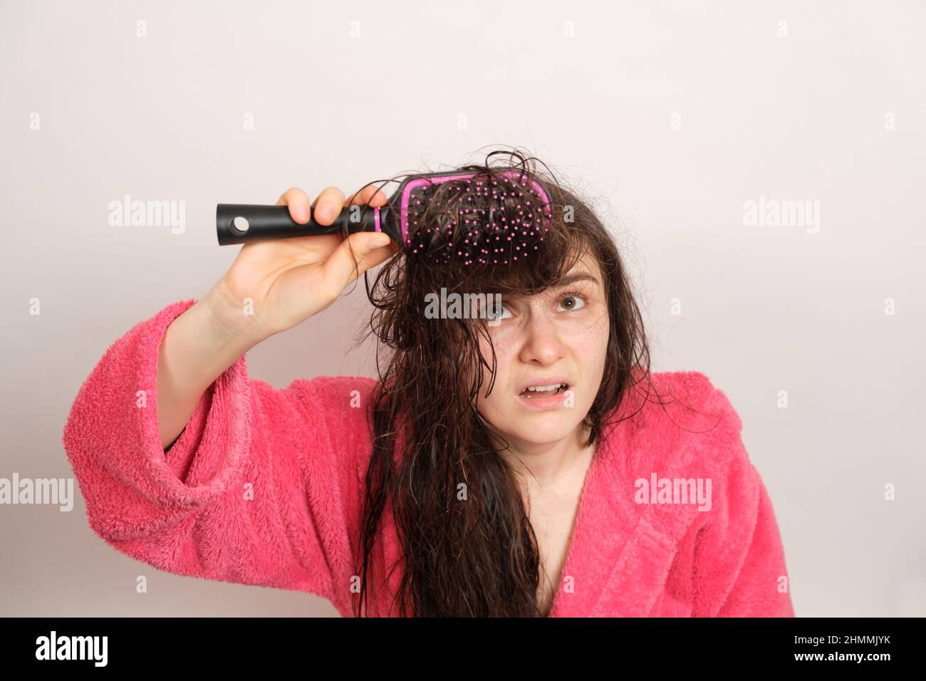 A woman tries to comb her tangled wet hair. Hair care at home, hair loss and section. Stock Photo