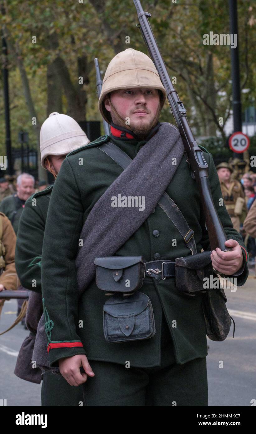 Reenactor dressed in old British Army Uniform with white helmet, carrying a rifle, looks ahead as he marches in the Lord Mayor’s show 2021, London. Stock Photo