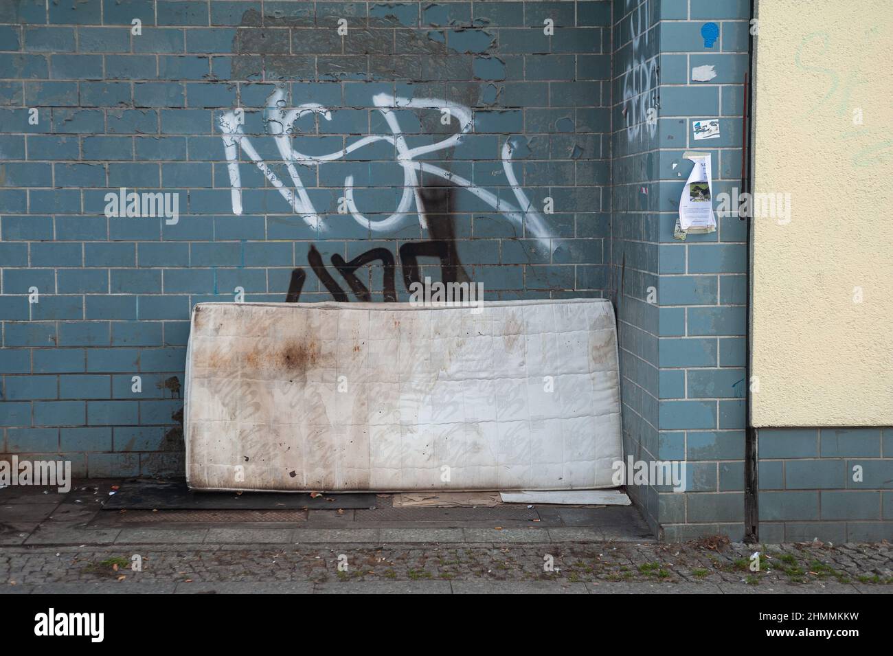 16.12.2021, Berlin, Germany, Europe - Old, filthy and illegally discarded mattress leans against a building wall smeared with graffiti at a roadside. Stock Photo