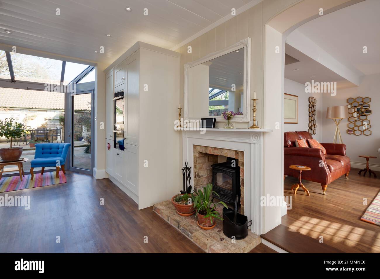 Hemingford Grey, Cambridgeshire - Feb 10 2018: Stylish luxury kitchen with fireplace and wood burner stove on brick hearth open to sitting room lounge Stock Photo