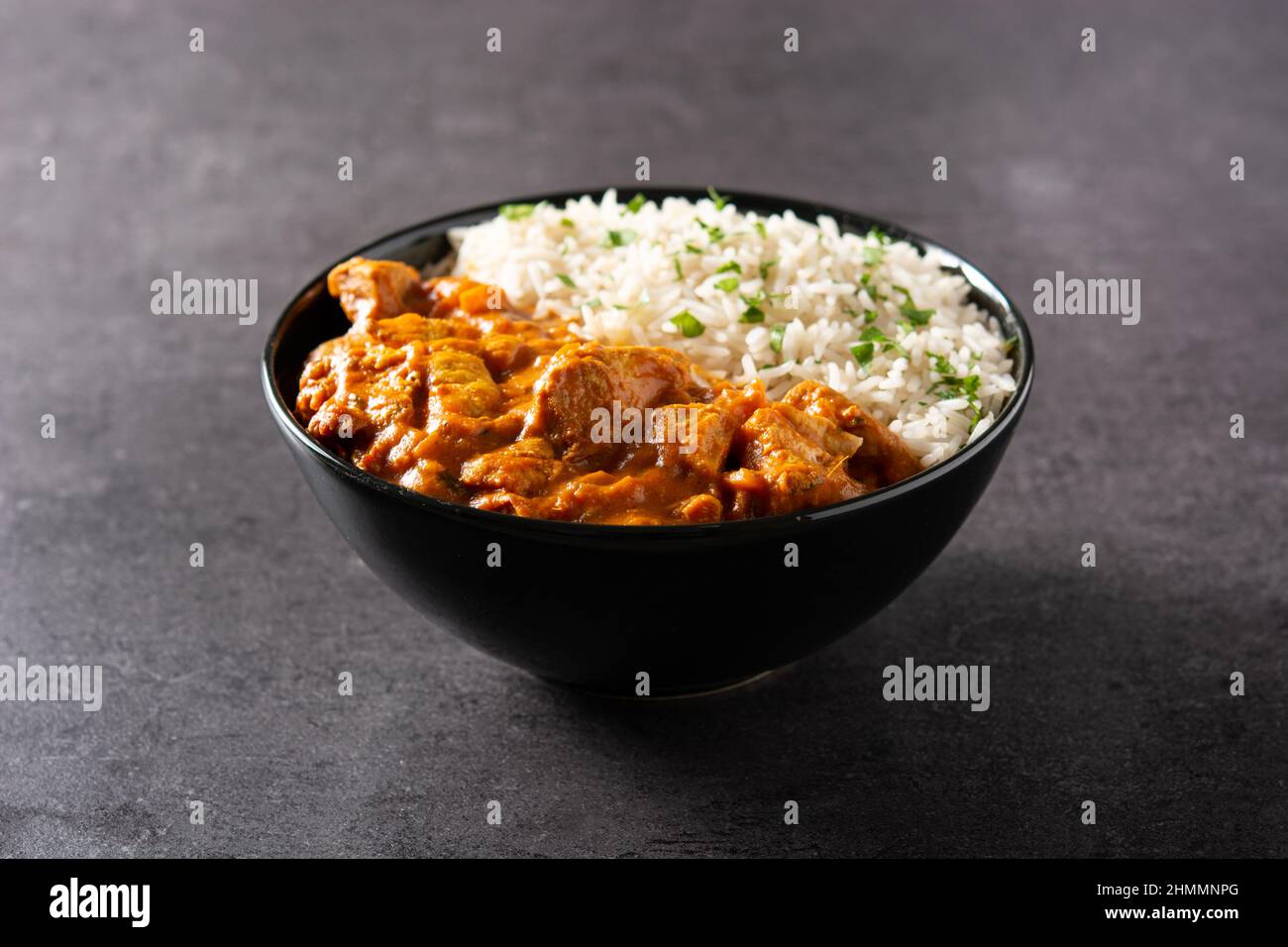 Indian butter chicken in black bowl on black background Stock Photo