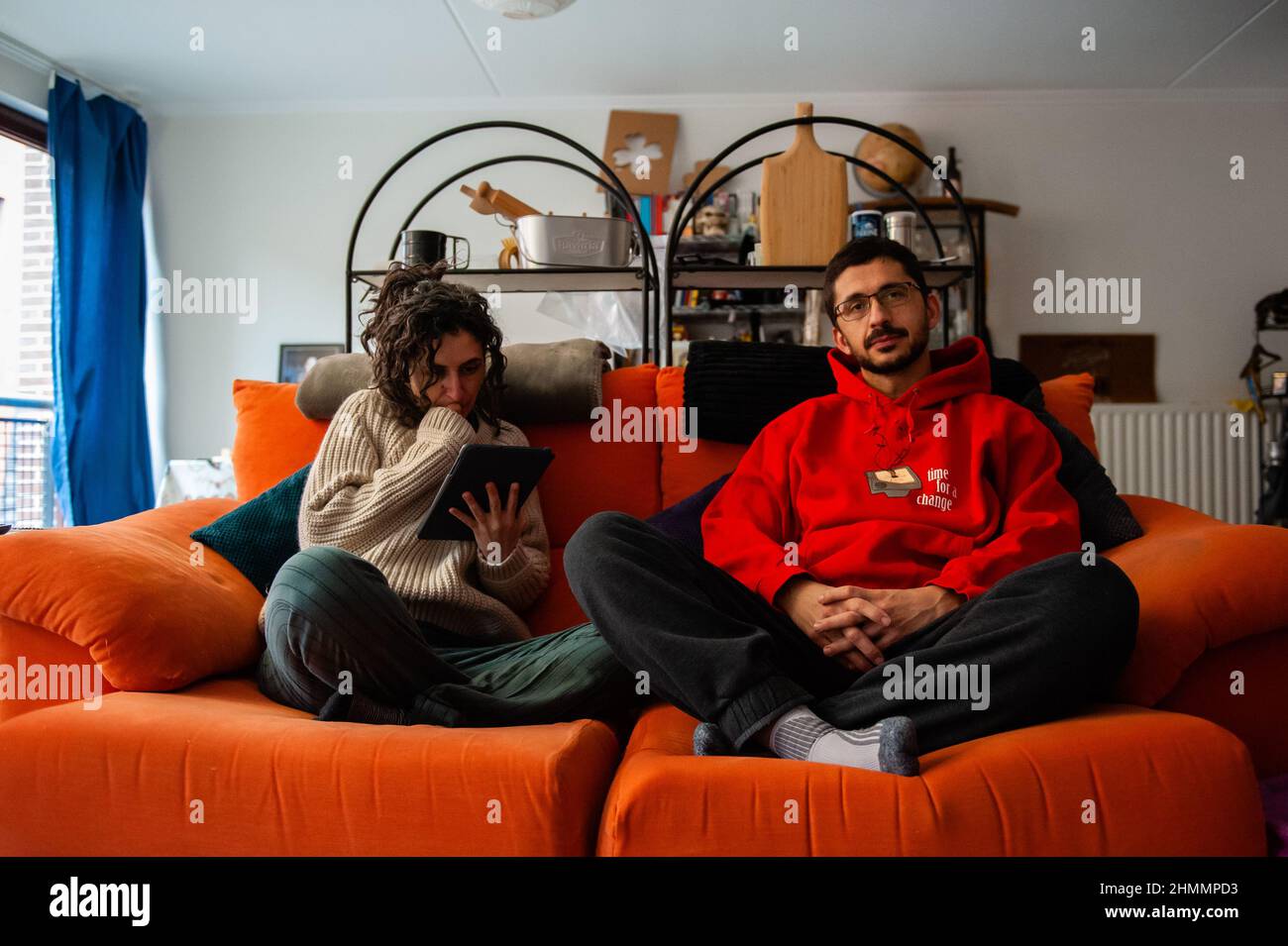 A couple is seen sitting on the couch at home after turning the heating  down and wearing cozy sweaters.Warm Sweater Day is organized every year on  a Friday in February by the '