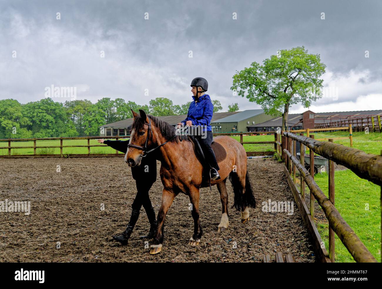 Girl having her first horse riding lesson bareback with hard hat helmet and instructor. Wellington Riding School, Hook, United Kingdom. 11.05.2016 Stock Photo