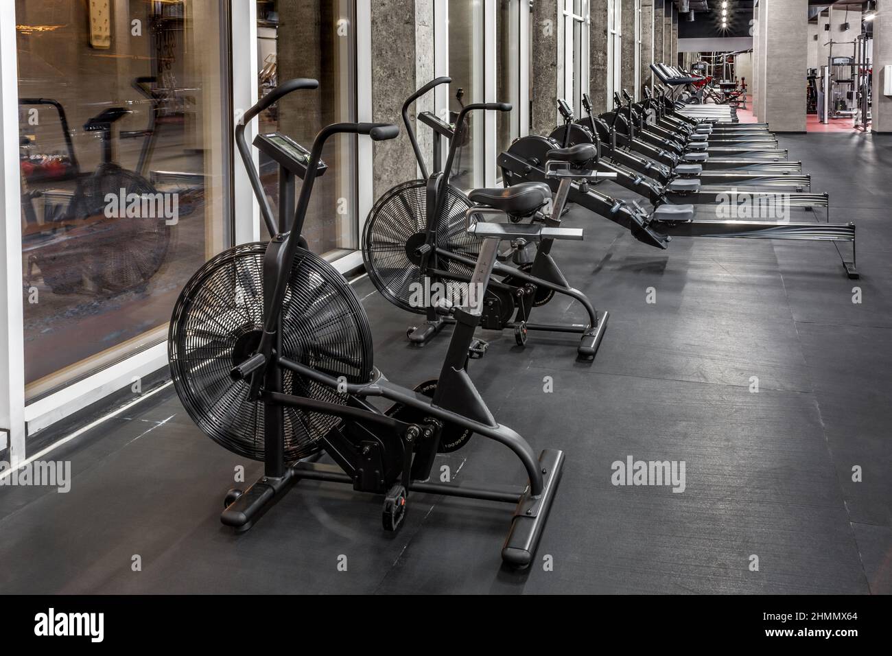 Exercise bikes, rowing machines and treadmills by window in spacious