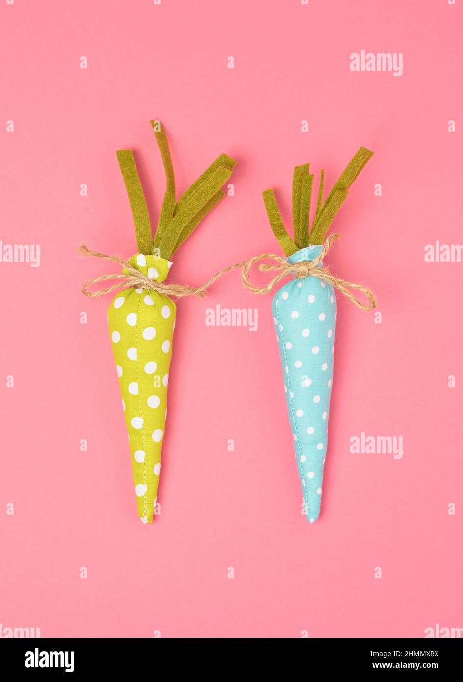 Two colorful decoration carrots on a pastel pink background. Easter bunny minimal concept. Stock Photo