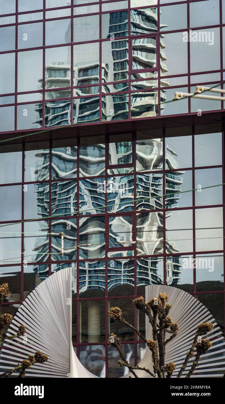 11 February 2022, Hessen, Frankfurt/Main: The Grand Tower is reflected distortedly in the window front of the DZ Bank. Completed in 2020, the tower in the Europaviertel is Germany's tallest residential high-rise at 180 meters. Below it is part of the sculpture 'The World' by Andreu Alfaro, which has adorned the square in front of the bank since 1986. Photo: Frank Rumpenhorst/dpa Stock Photo