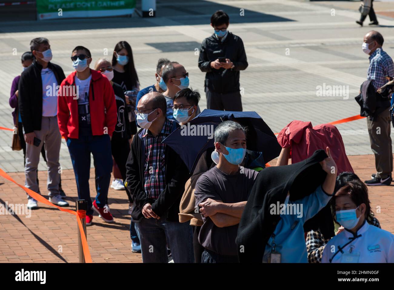 Hong Kong, China. 11th Feb, 2022. People queue at a temporary COVID test centre in Edinburgh Place in Central Hong Kong. Some try to take shelter from the sun under their coats. Credit: Marc R. Fernandes /Alamy Live News Stock Photo