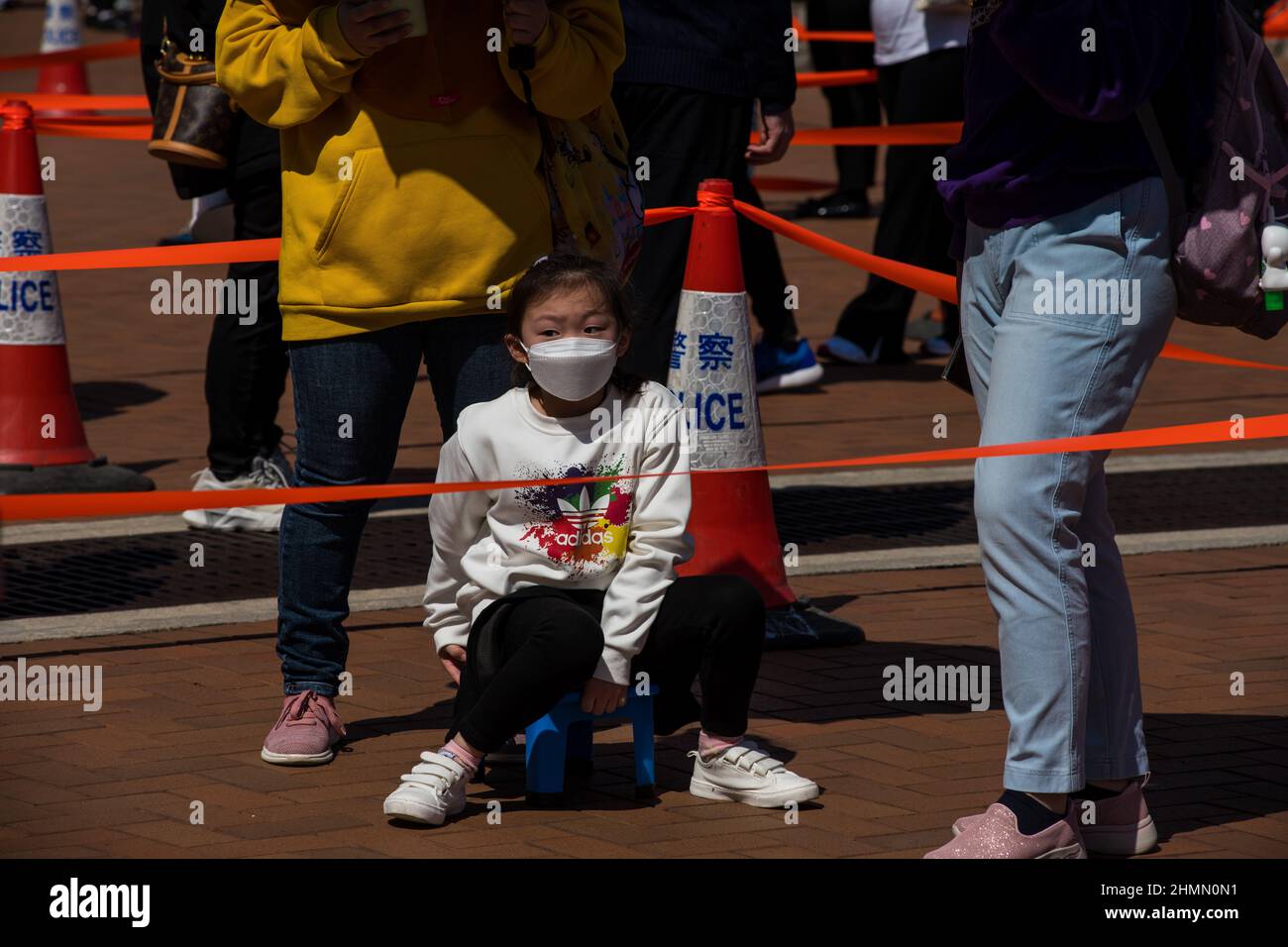 Hong Kong, China. 11th Feb, 2022. A child sits on a small chair as she queues up to get tested at a temporary COVID testing centre in Edinburgh Place, in Central Hong Kong. Credit: Marc R. Fernandes /Alamy Live News Stock Photo