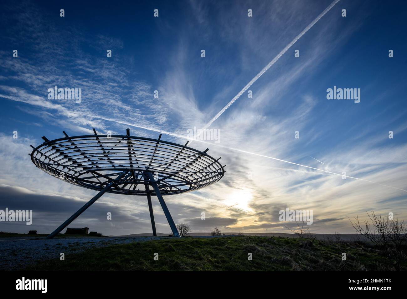 Haslingden, Lancashire, UK, Wednesday February 09, 2022. A walker stops to admire the setting sun at the Halo panopticon above the town of Haslingden, Stock Photo