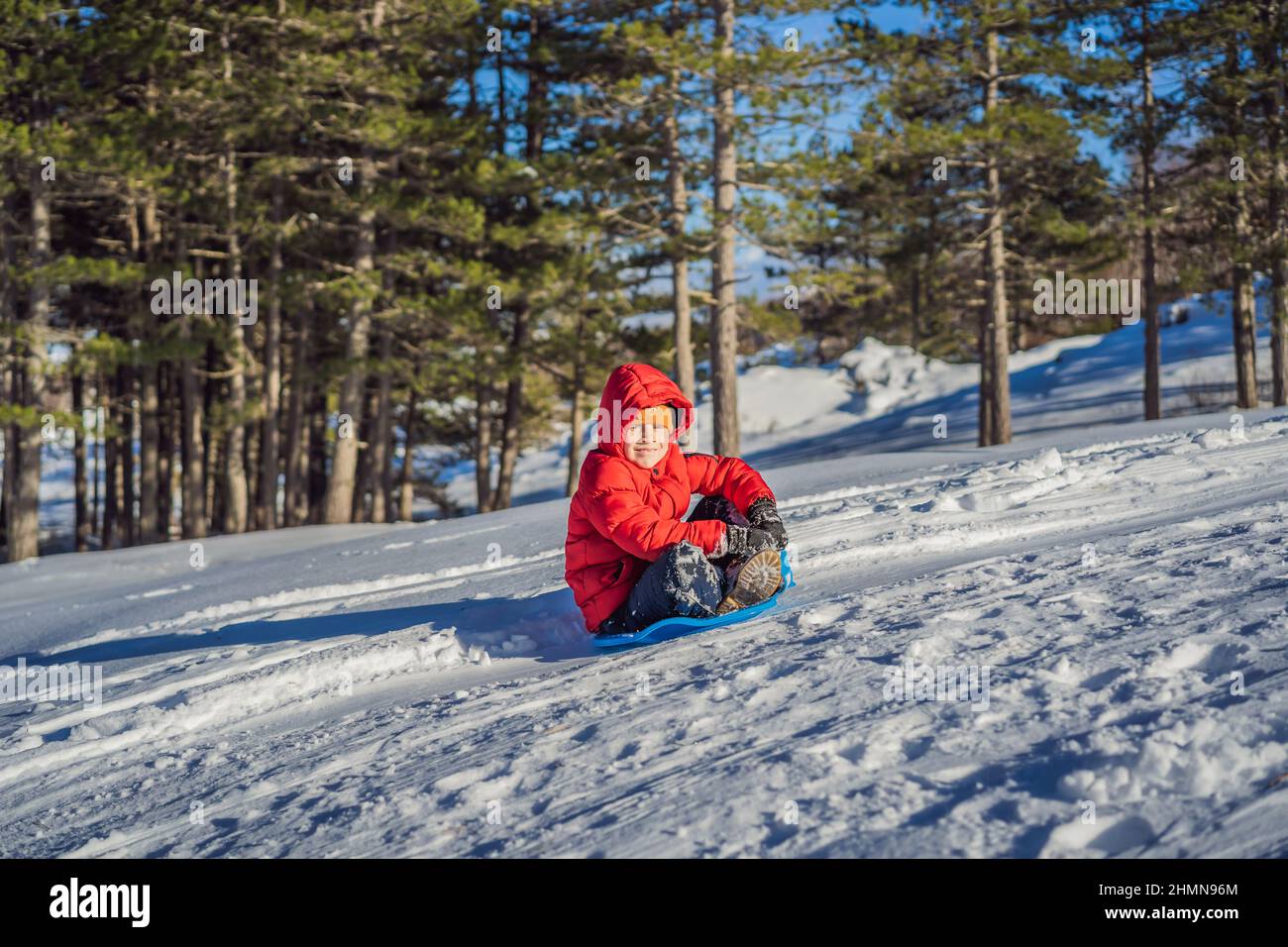 happy and positive little boy enjoying sledding and cold weather ...