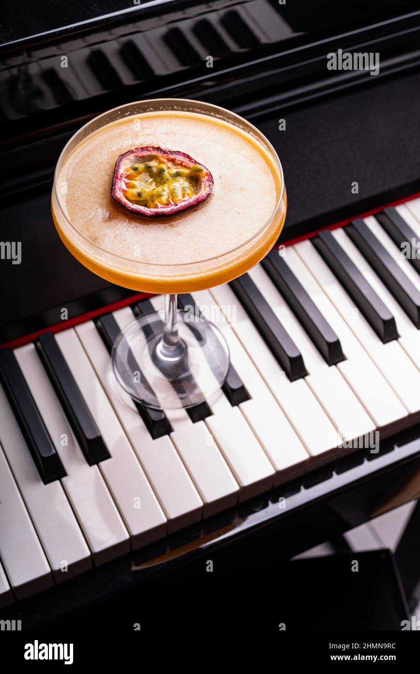 Pornstar Martini cocktail garnished with half of a passionfruit on a piano keyboard Stock Photo
