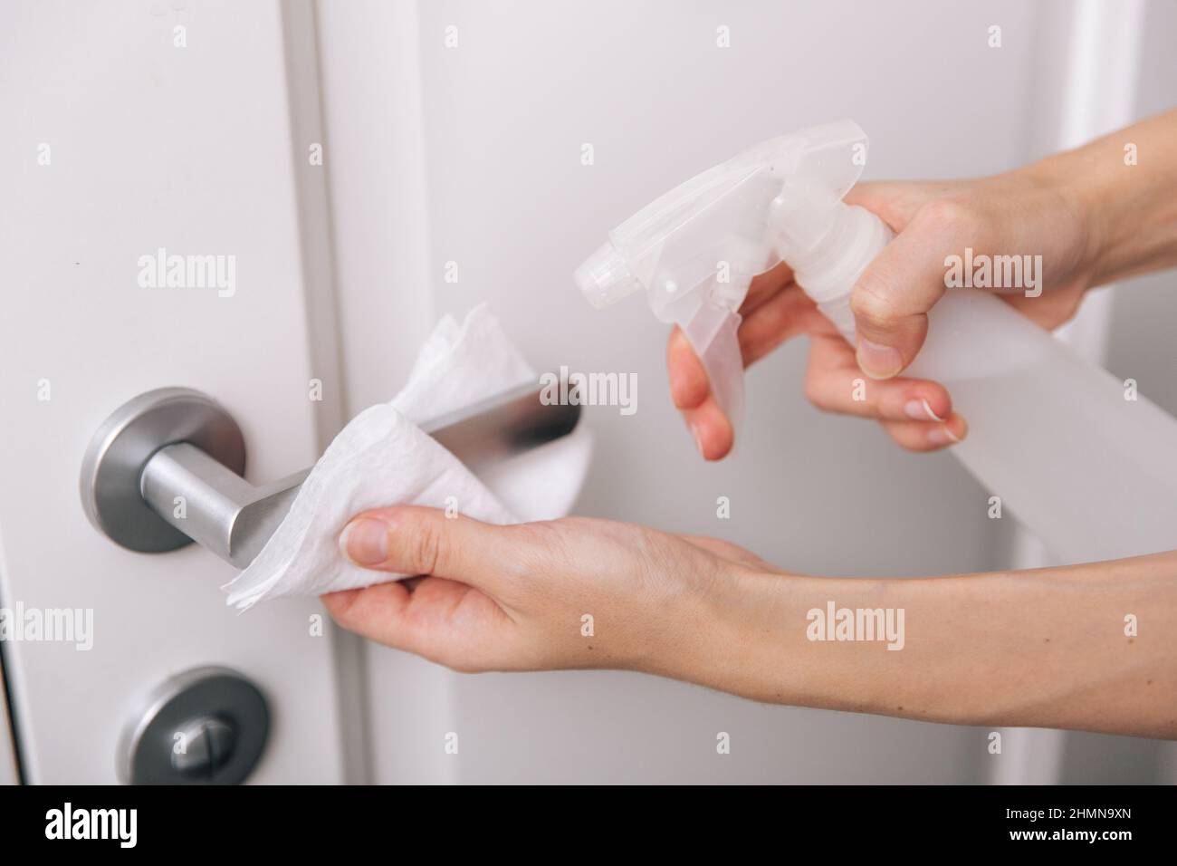 Cleaning white door handles with an antiseptic wet wipe and sanitizer