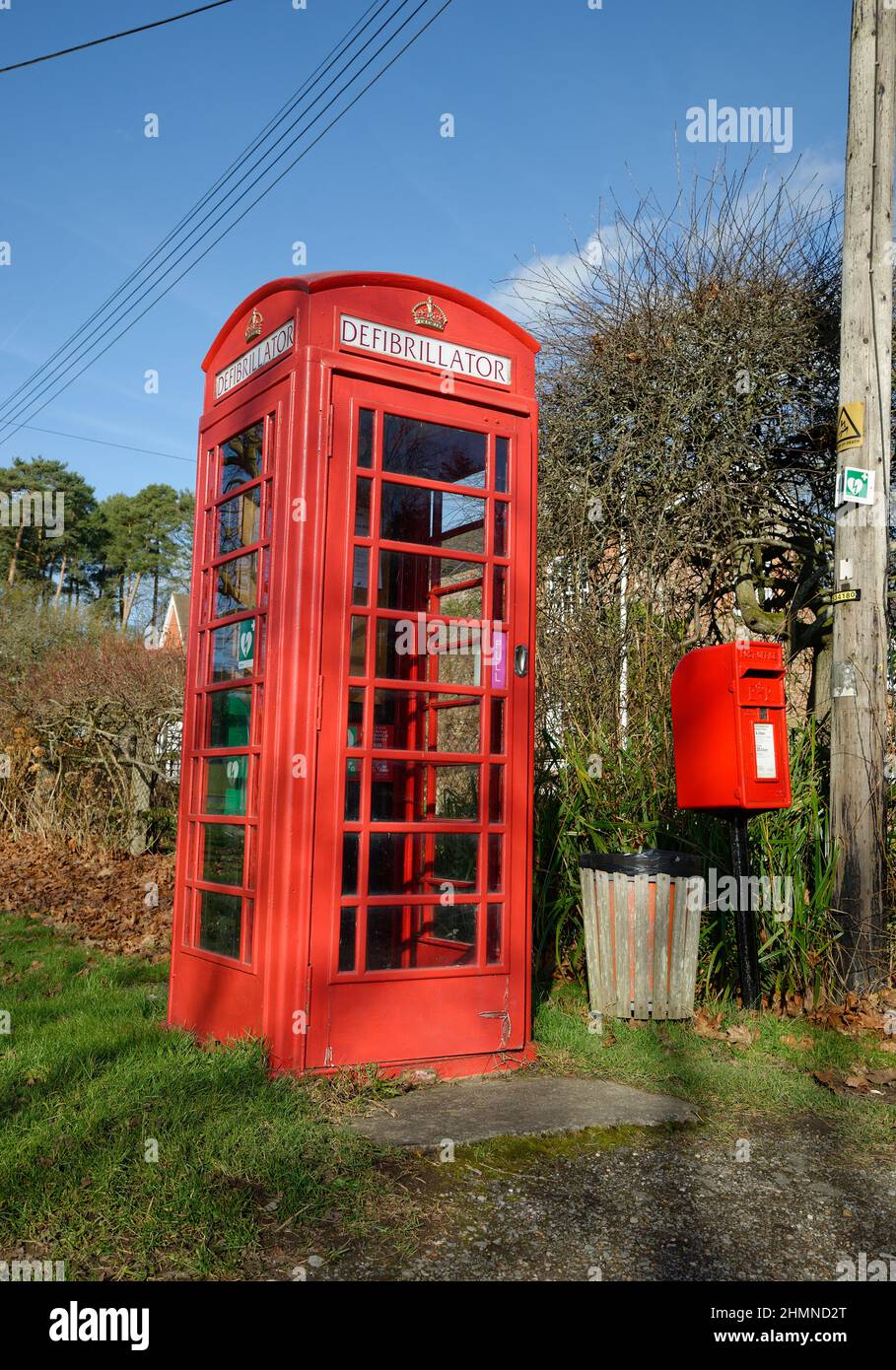 A red telephone box that has been converted to house a Defibrillator. Situated on the village green of Staplefield, West Sussex, UK Stock Photo