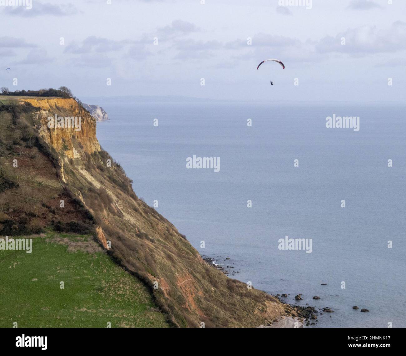 Sidmouth, Devon, 11th Feb 22 A paraglider takes advantage of the warm, still weather to fly out over Salcombe Mouth, near Sidmouth. Credit: Photo Central/Alamy Live News Stock Photo