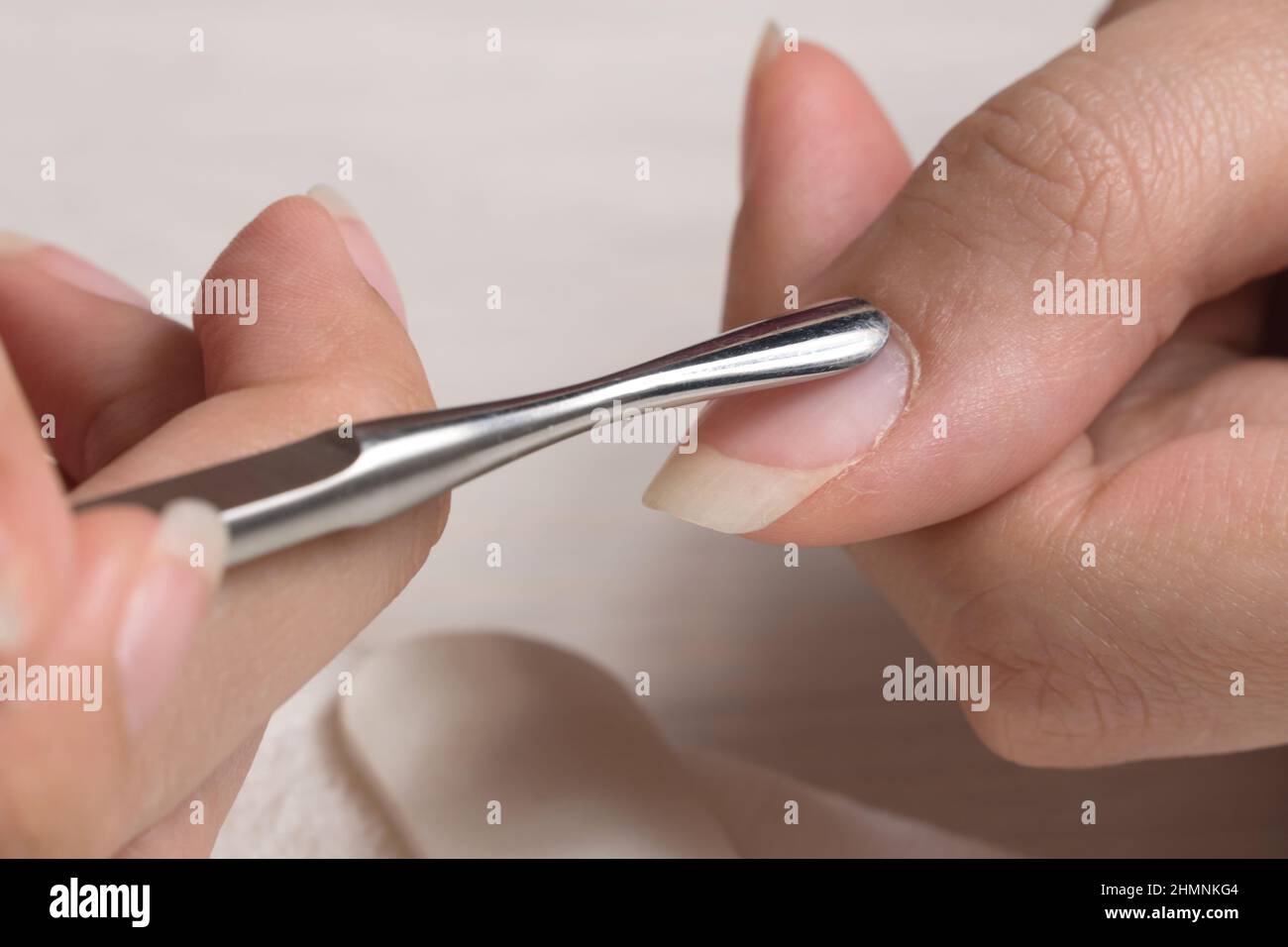 Manicure. Push back the cuticle with a metal pusher. Getting injured during a manicure. Skin care, hygiene. Spa, nail salon. Home care. Beauty. Stock Photo