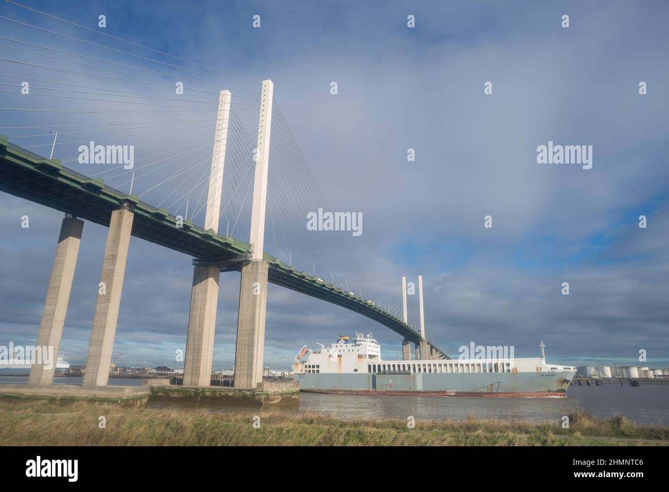 Dartford-Thurrock river crossing a cable-stayed bridge with Thames at low tide with cargo ship Ferry Wilhelminde sailing beneath just left Purfleet Stock Photo