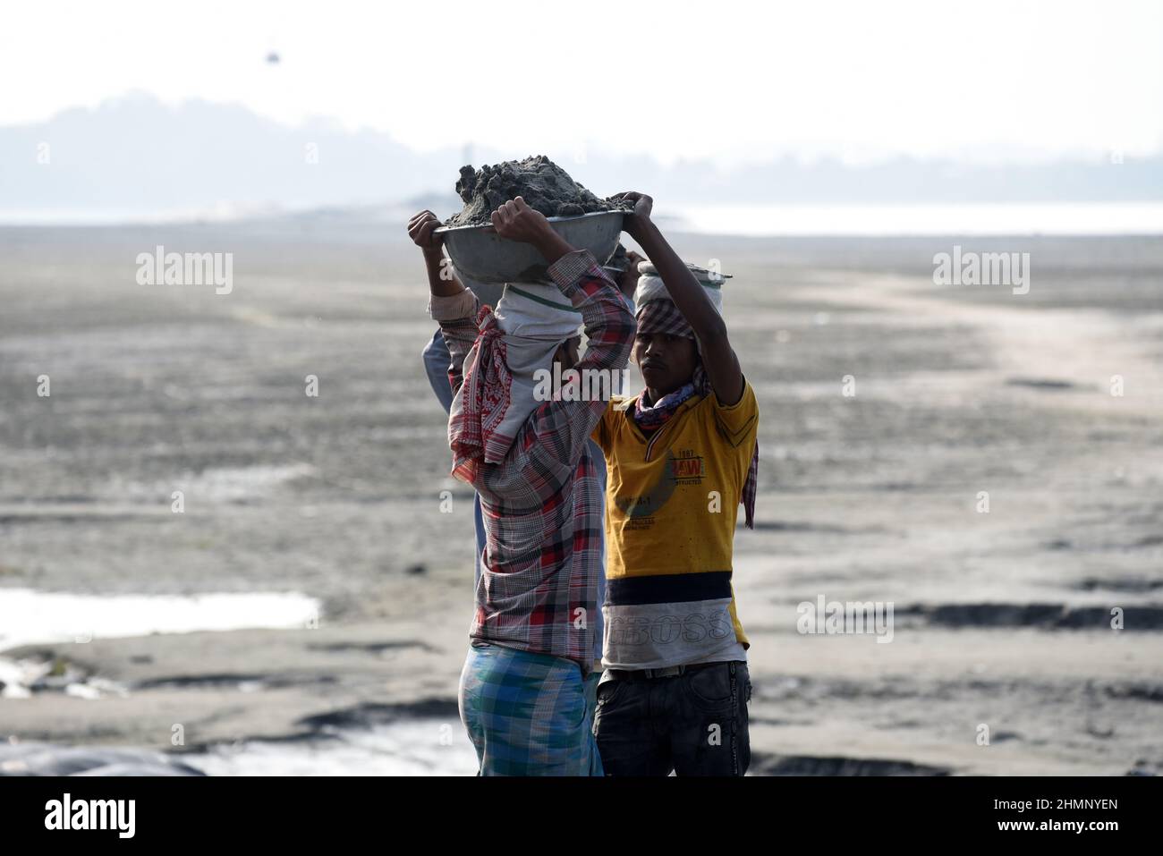 Guwahati, India. 07 February 2022. Laborer carries soil from a river bank as they filling