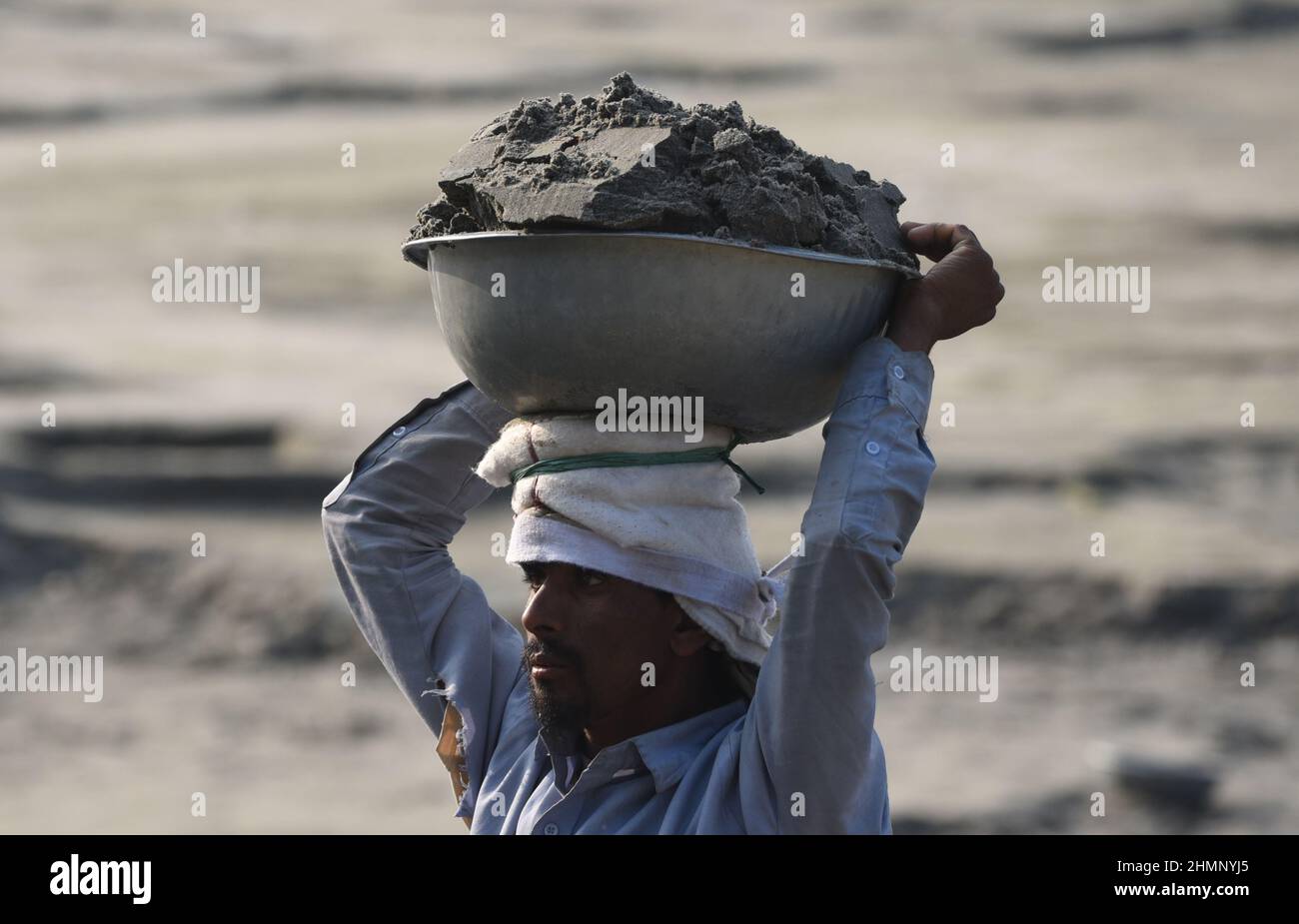 Guwahati, India. 07 February 2022. Laborer carries soil from a river bank as they filling