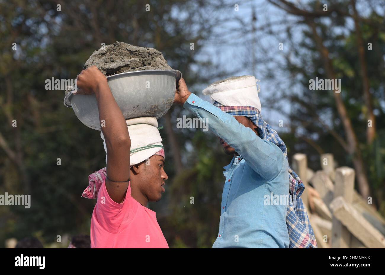Guwahati, India. 07 February 2022. Laborer carries soil from a river bank as they filling