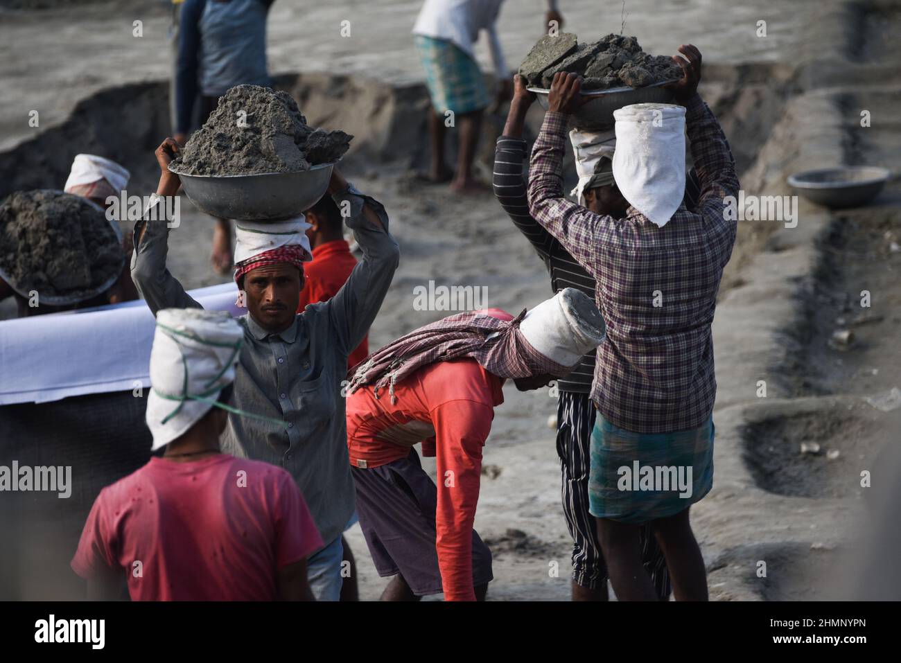 Guwahati, India. 07 February 2022. Laborer carries soil from a river bank as they filling