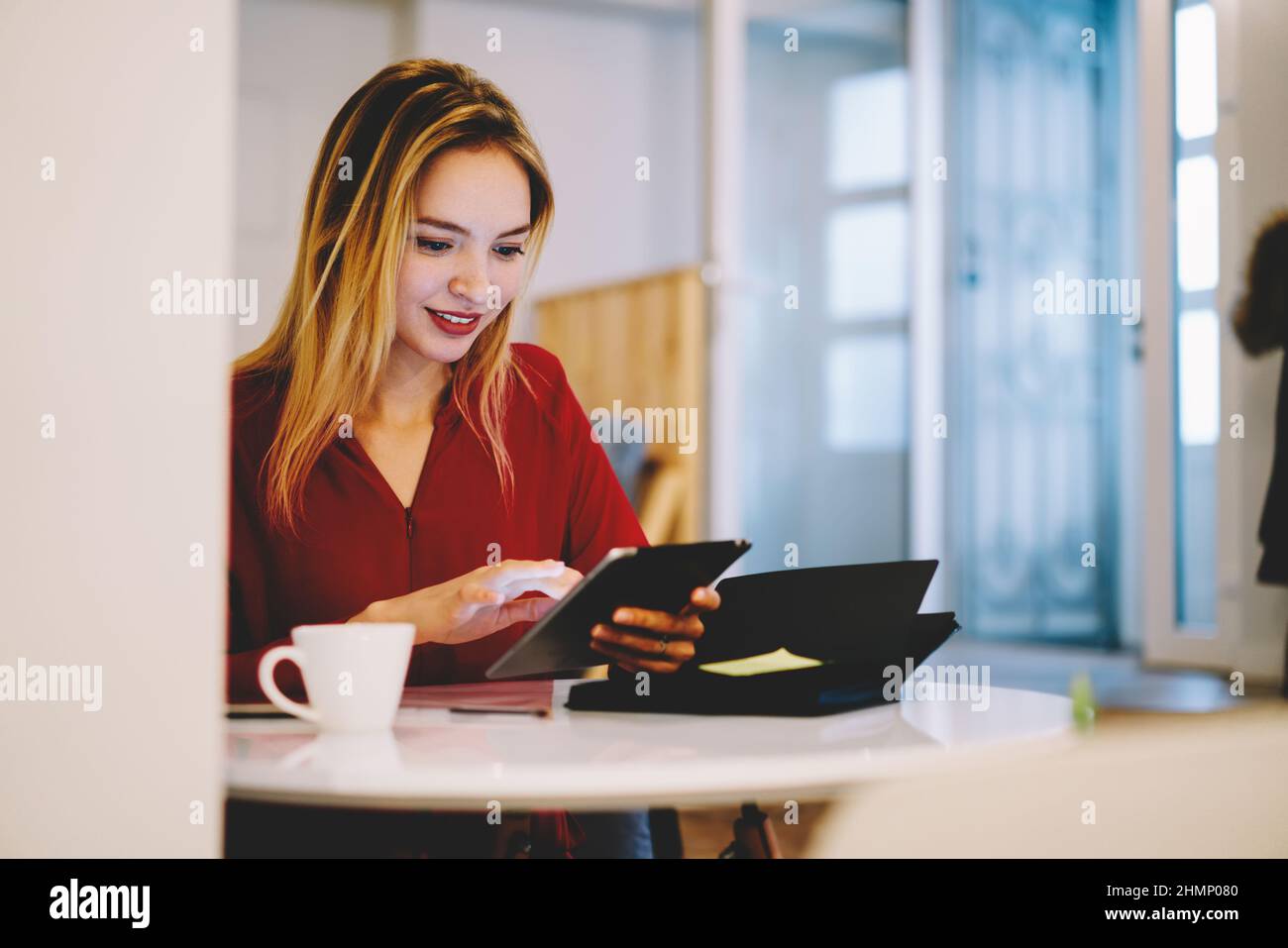 Freelancer browsing tablet in light workspace Stock Photo