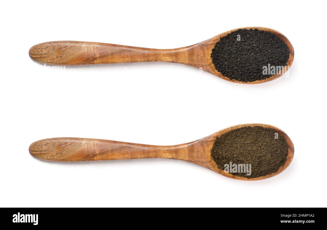 nigella sativa in seeds and powdered form in wooden spoons, also known as black seeds, black cumin or caraway or kalonji, isolated on white background Stock Photo