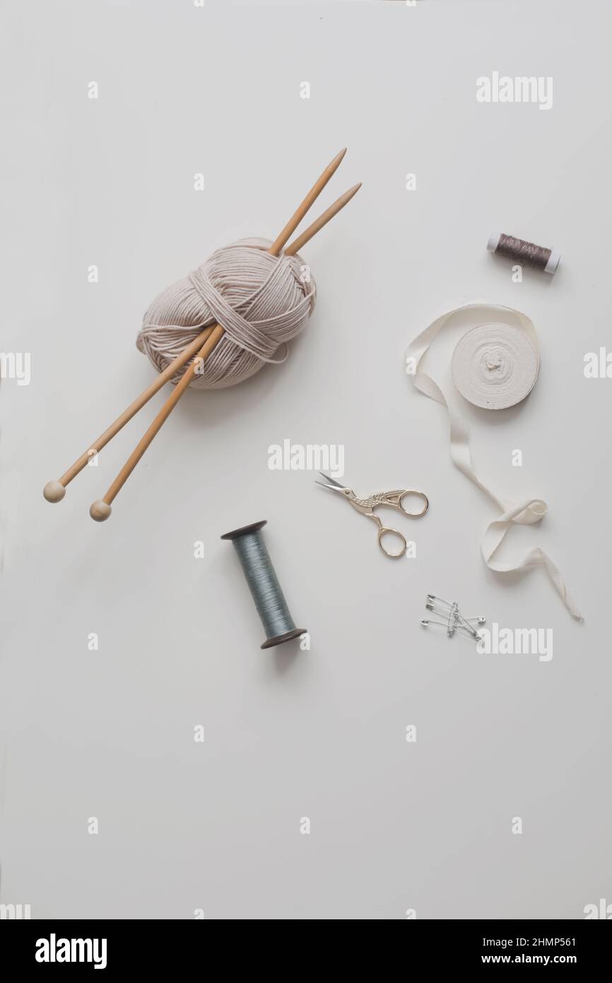 Top view of scissors, threads, knitting needles and sewing supplies on a white background. Concept of craft hobby, knitting and sewing Stock Photo