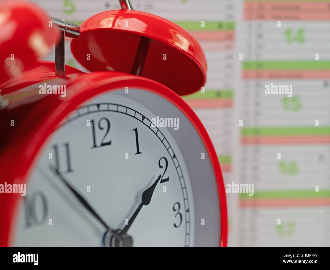 Red alarm clock in front of a calendar Stock Photo