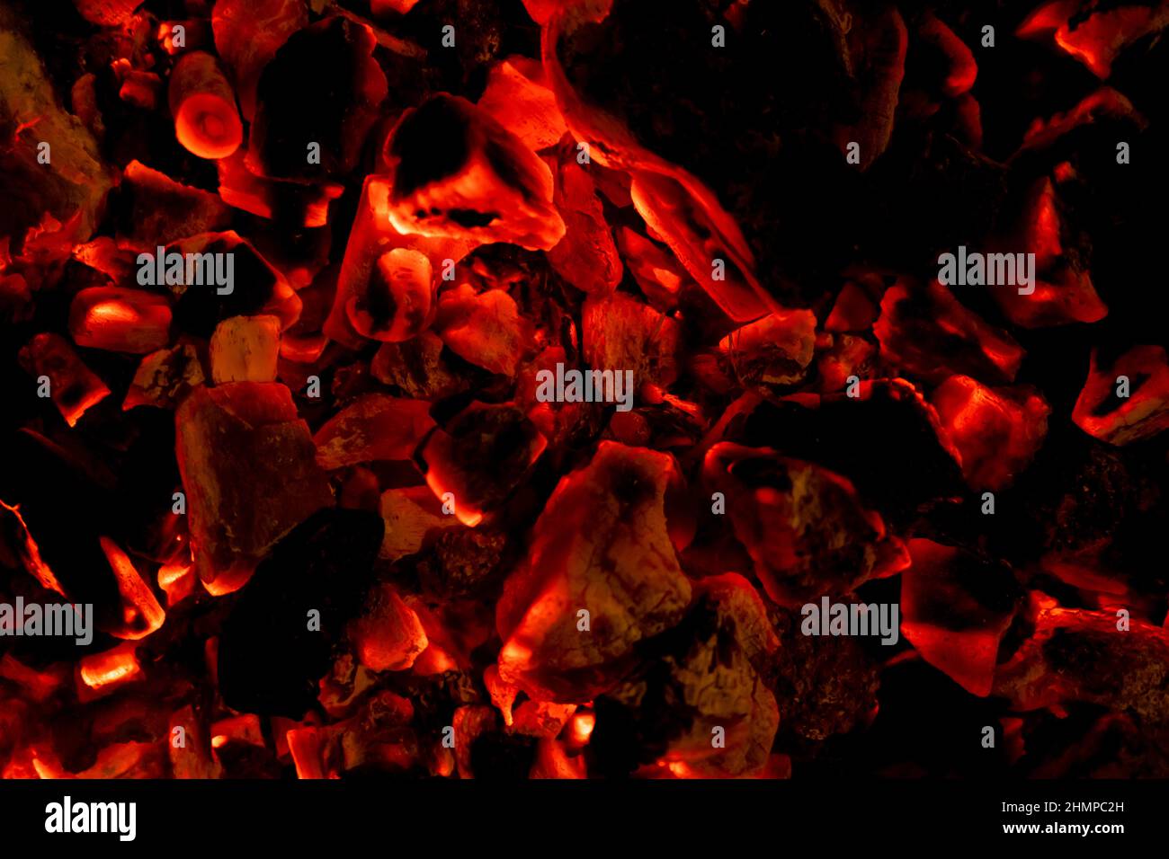 Glowing embers in hot red color, abstract background. The hot embers of burning wood log fire. Firewood burning on grill. Texture fire bonfire embers Stock Photo