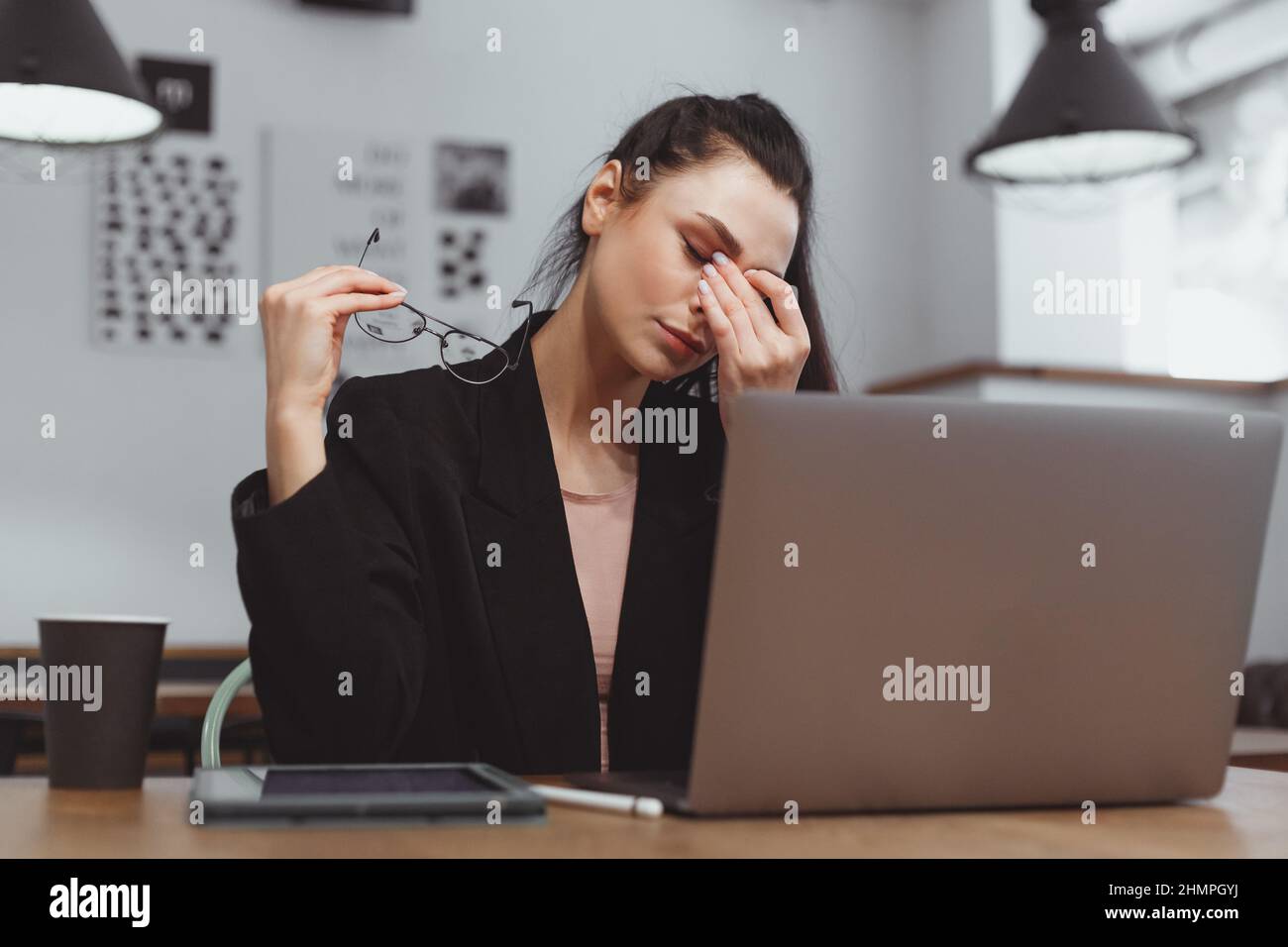 Young woman feel eye fatigue during working on laptop. Take off glasses
