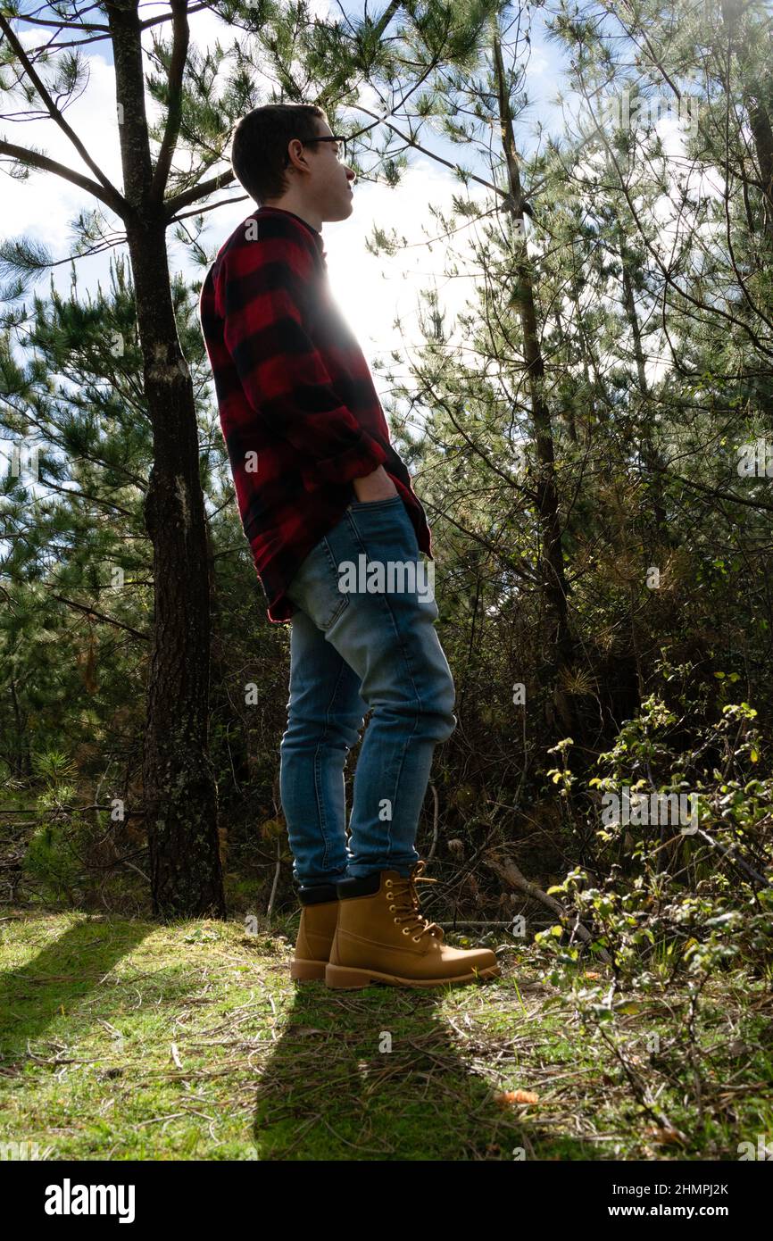 Man in a lumberjack shirt standing in a forest with his hands in his pockets, Spain Stock Photo