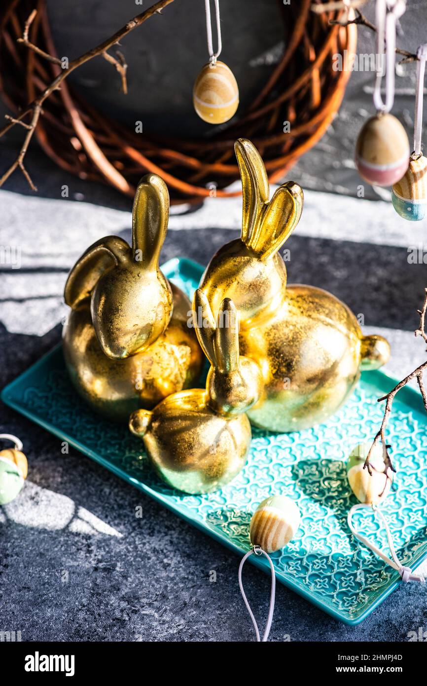 Festive golden Easter bunny decorations on a table with Easter eggs Stock Photo