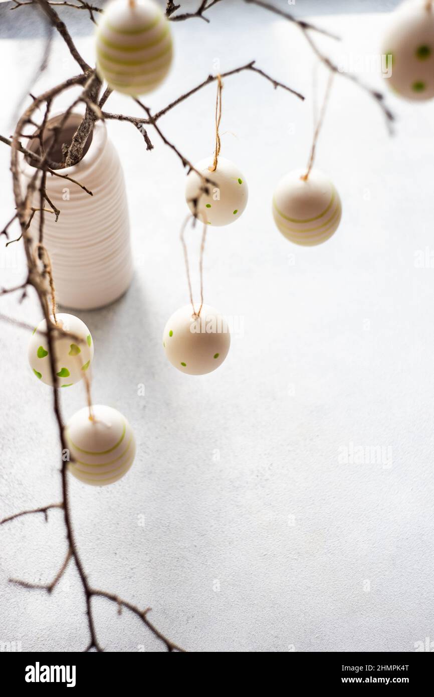 Painted Easter egg decorations hanging on branches in a vase Stock Photo