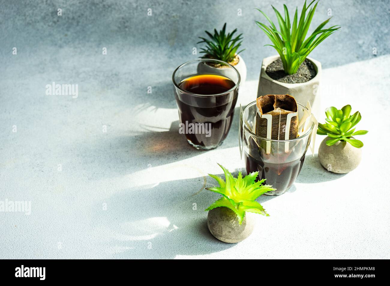Individual coffee filter and coffee drink next to houseplants Stock
