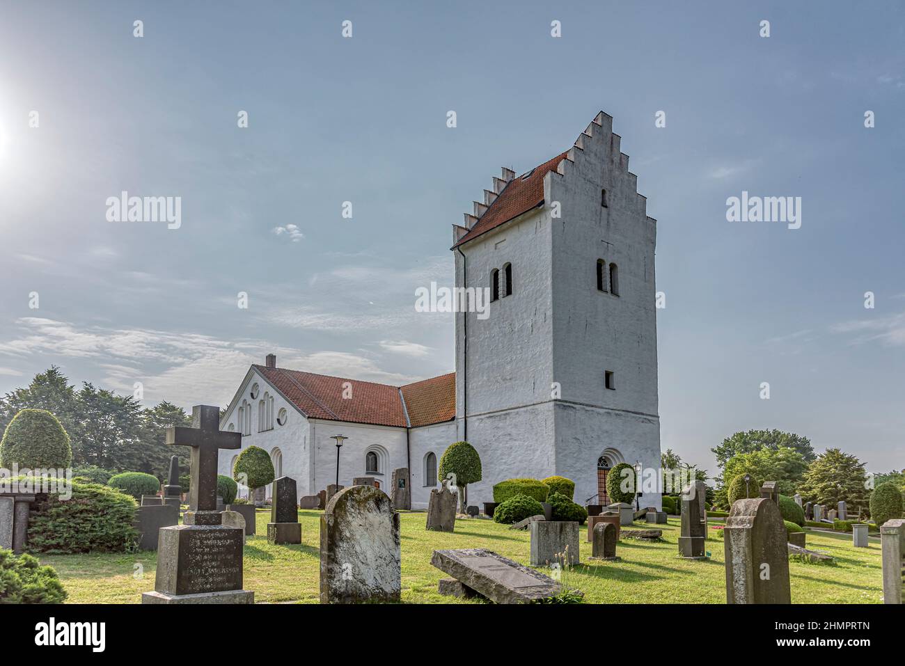 a white swedish church with a high tower, in the soft sunshine, Skurup, Sweden, July 16, 2021 Stock Photo