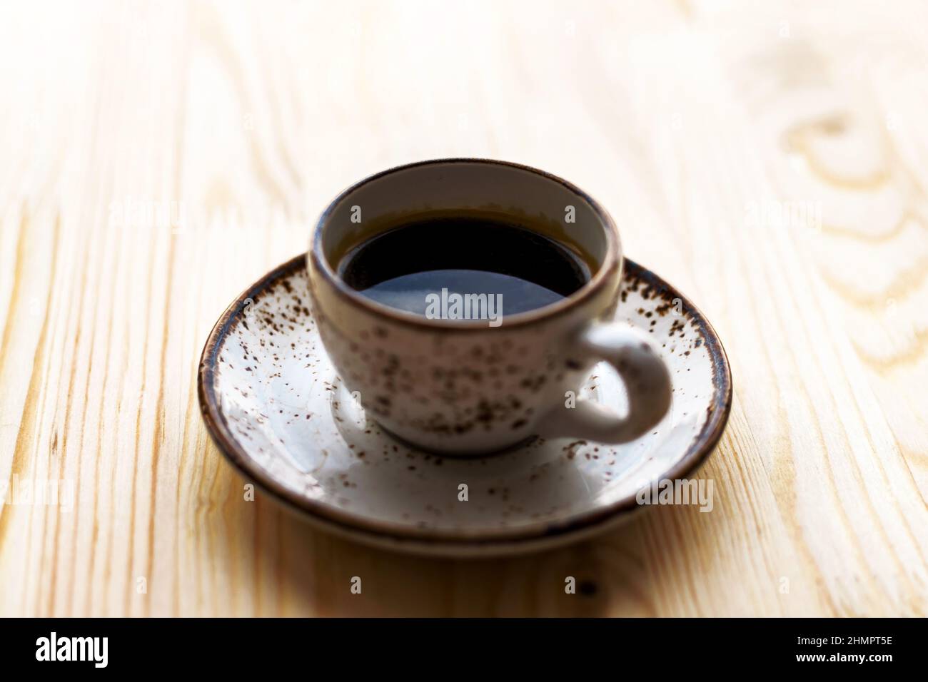 Cup of Coffee espresso on saucer on wooden table background. Sunny morning breakfast concept. Stock Photo