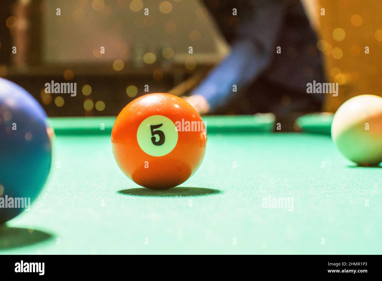 In this photo you can see a boy ready to hit the orange pool ball