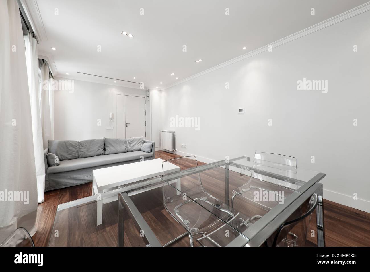 furnished apartment living room with glass table and gray sofa