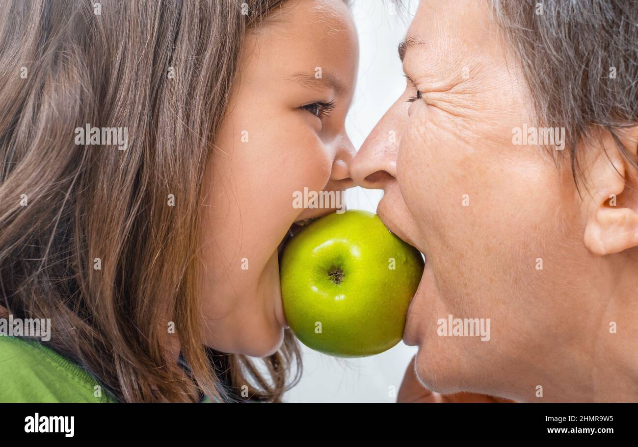 Senior and child girl bite one green apple together Stock Photo