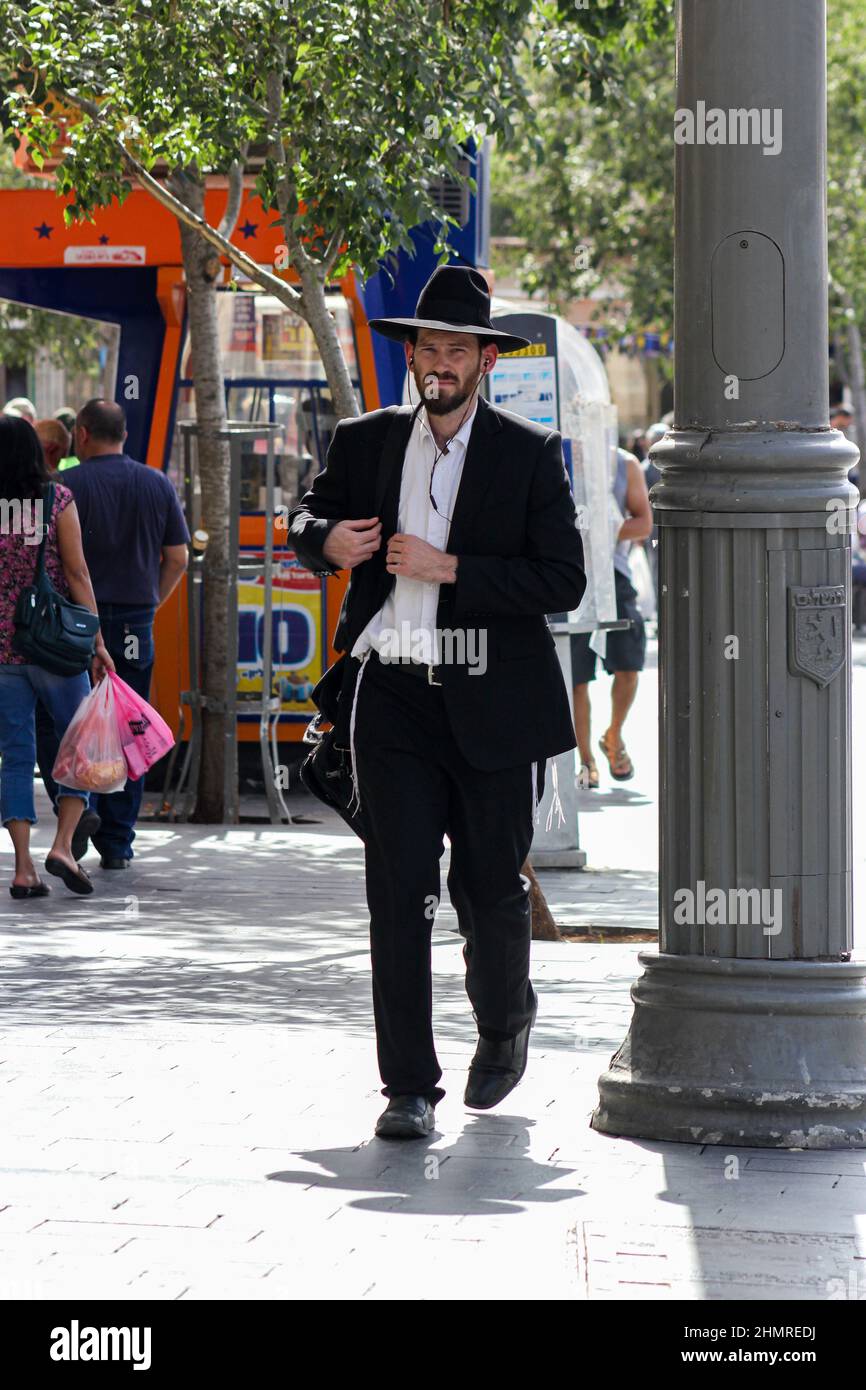 A Jewish man in a black hat walks the sidewalk in Jerusalem, Israel. Stock Photo
