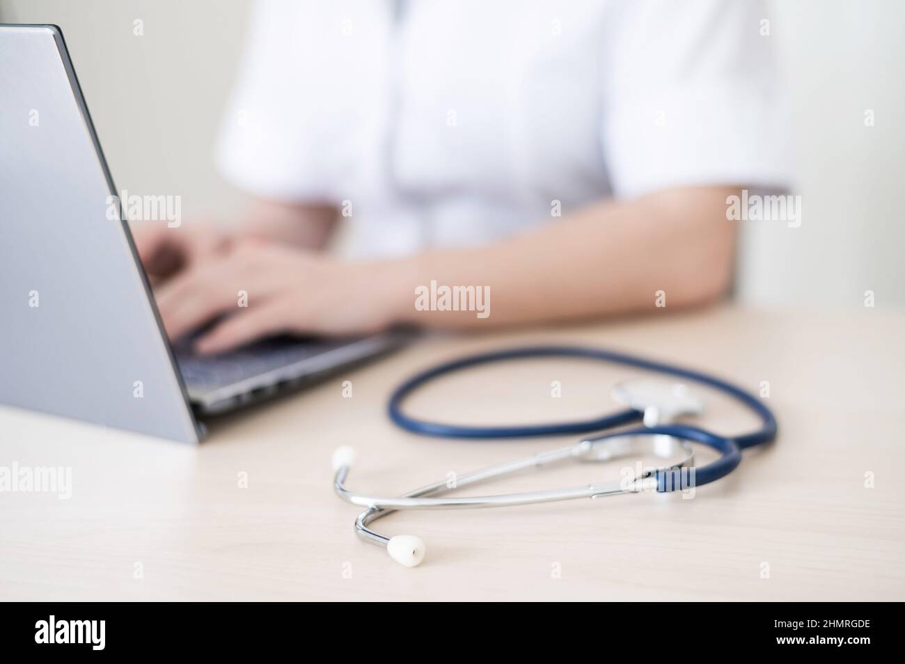 Unrecognizable female doctor in uniform uses a laptop. Faceless medical ...