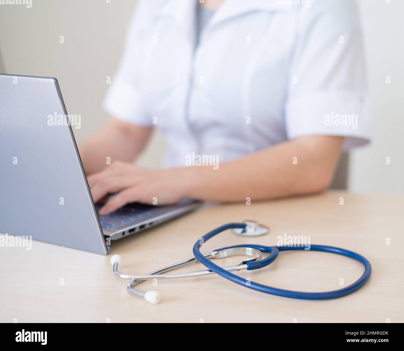 Unrecognizable female doctor in uniform uses a laptop. Faceless medical ...