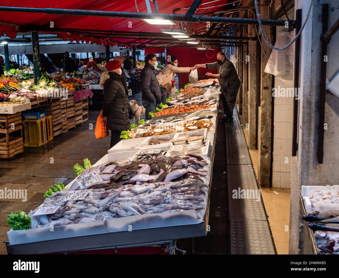 Venice, Italy - January 5 2022: Customers Shopping at Rialto Fish Market or Mercato del Pesce al Minuto at Rialto in Venice with Covid Restrictions. Stock Photo