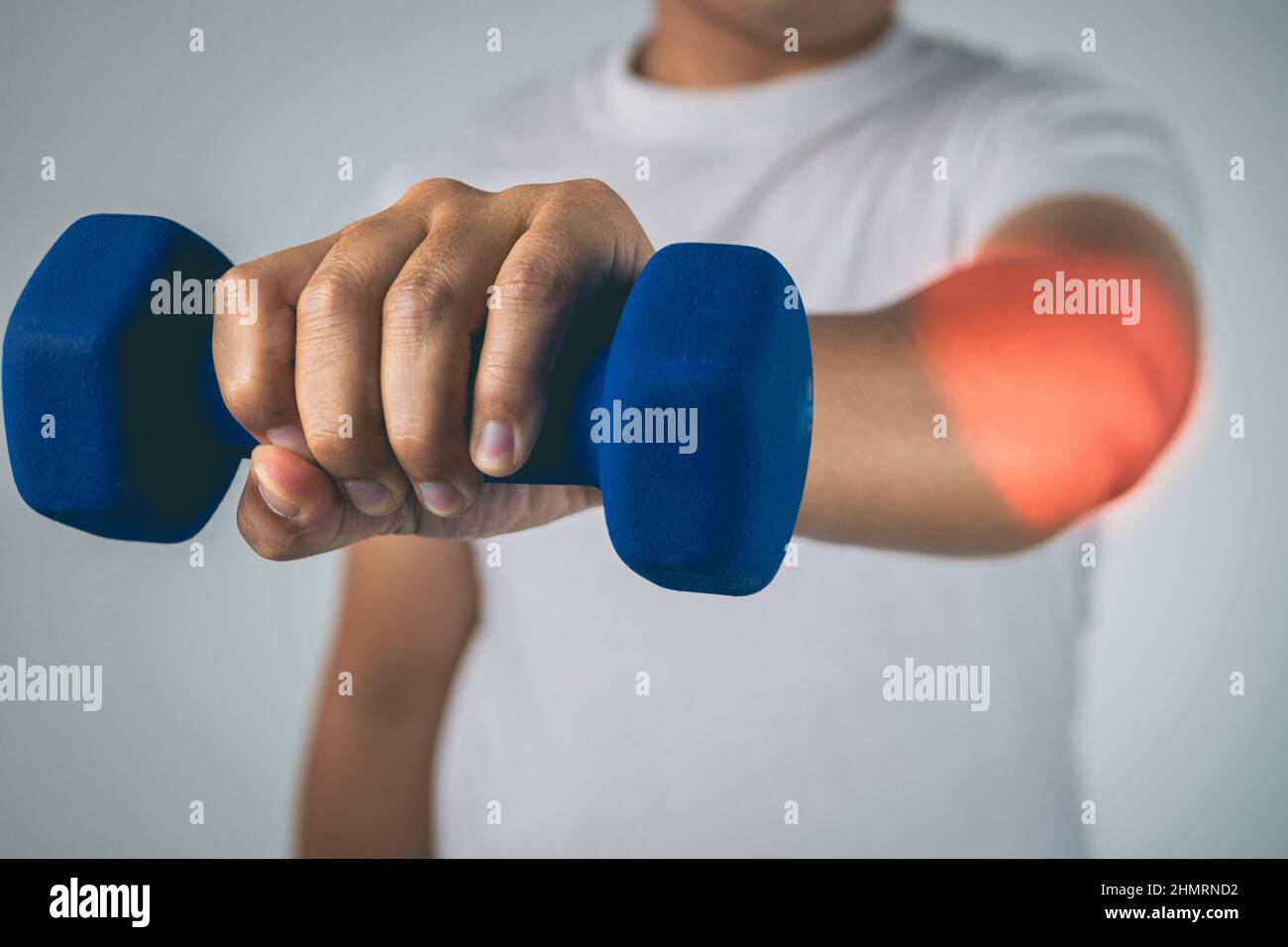 Tennis elbow concept. The man uses a blue dumbbell to physical therapy. Pain symptom area is shown with red color. Healthcare knowledge. Medium close Stock Photo