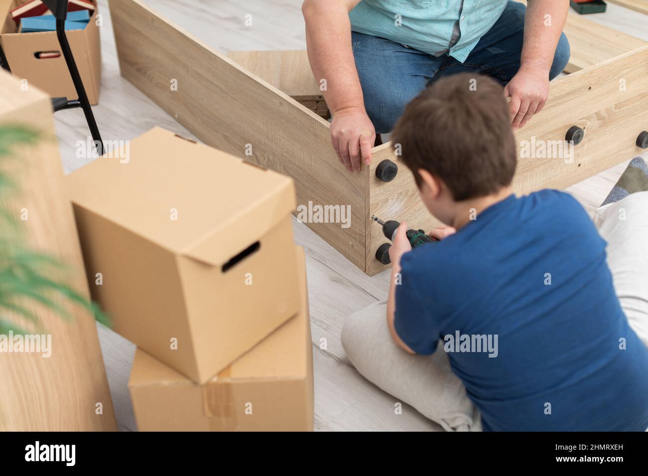 A son tightens a screw in a folding bookcase with a screwdriver Stock